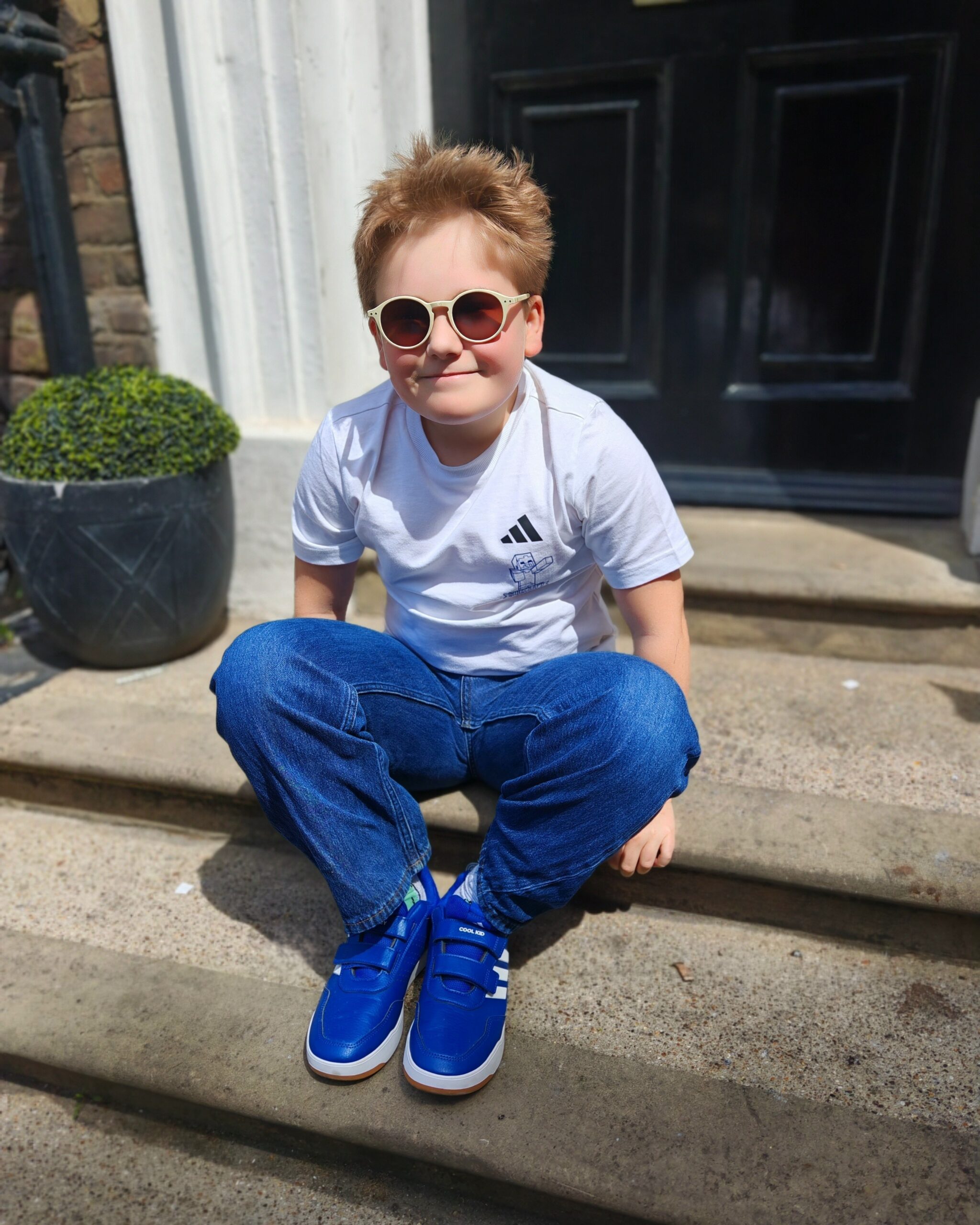 White boy seating on a the staircases outside London. He's wearing a white tee and matching sunglasses. White boy seating on a the staircases outside London. He's wearing a white tee and matching sunglasses.