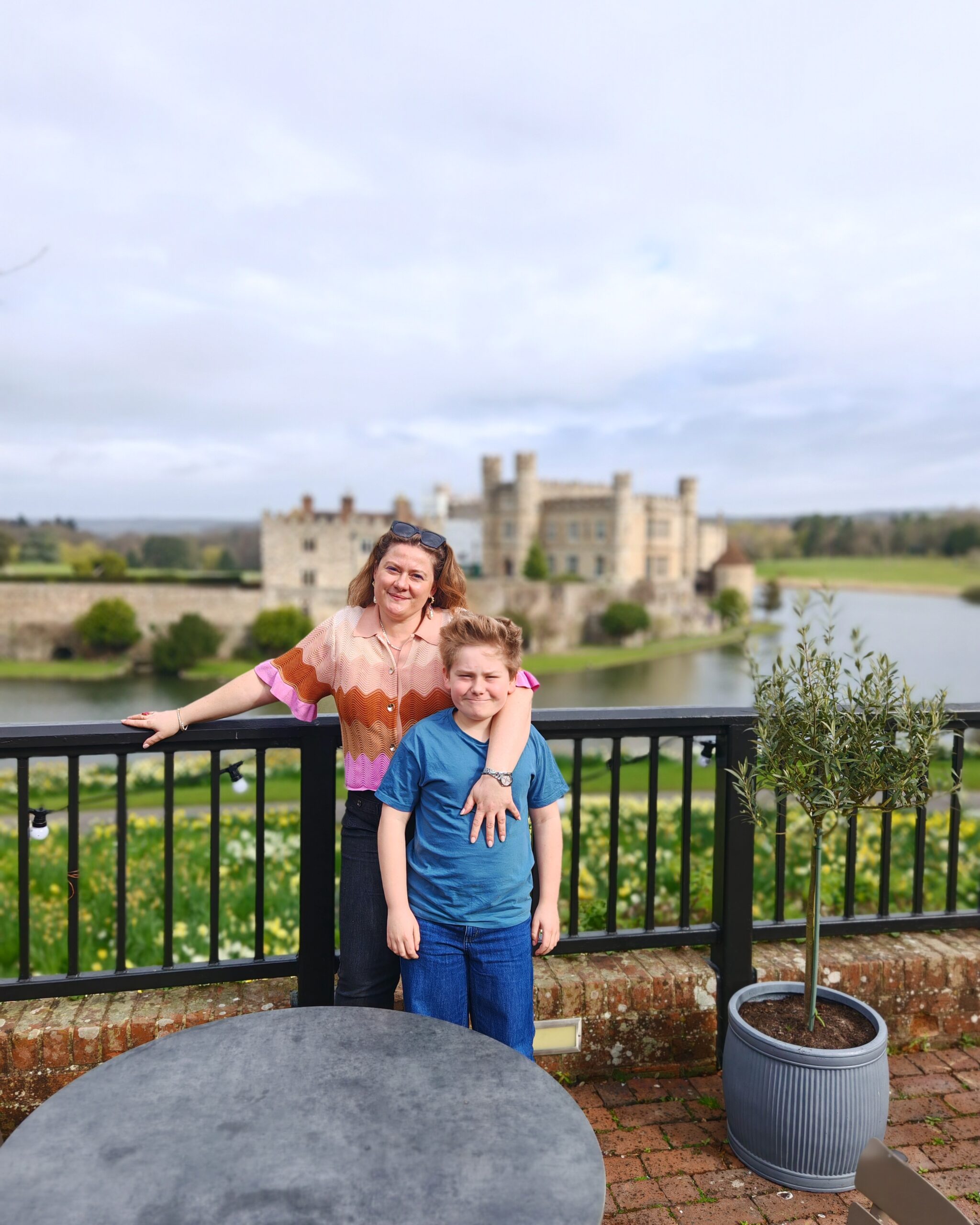 A mum and her son looking over Leeds Castle from the view point of the restaurant. She's wearing a pink top and you can see the famous Kent Castle in the background. A mum and her son looking over Leeds Castle from the view point of the restaurant. She's wearing a pink top and you can see the famous Kent Castle in the background.