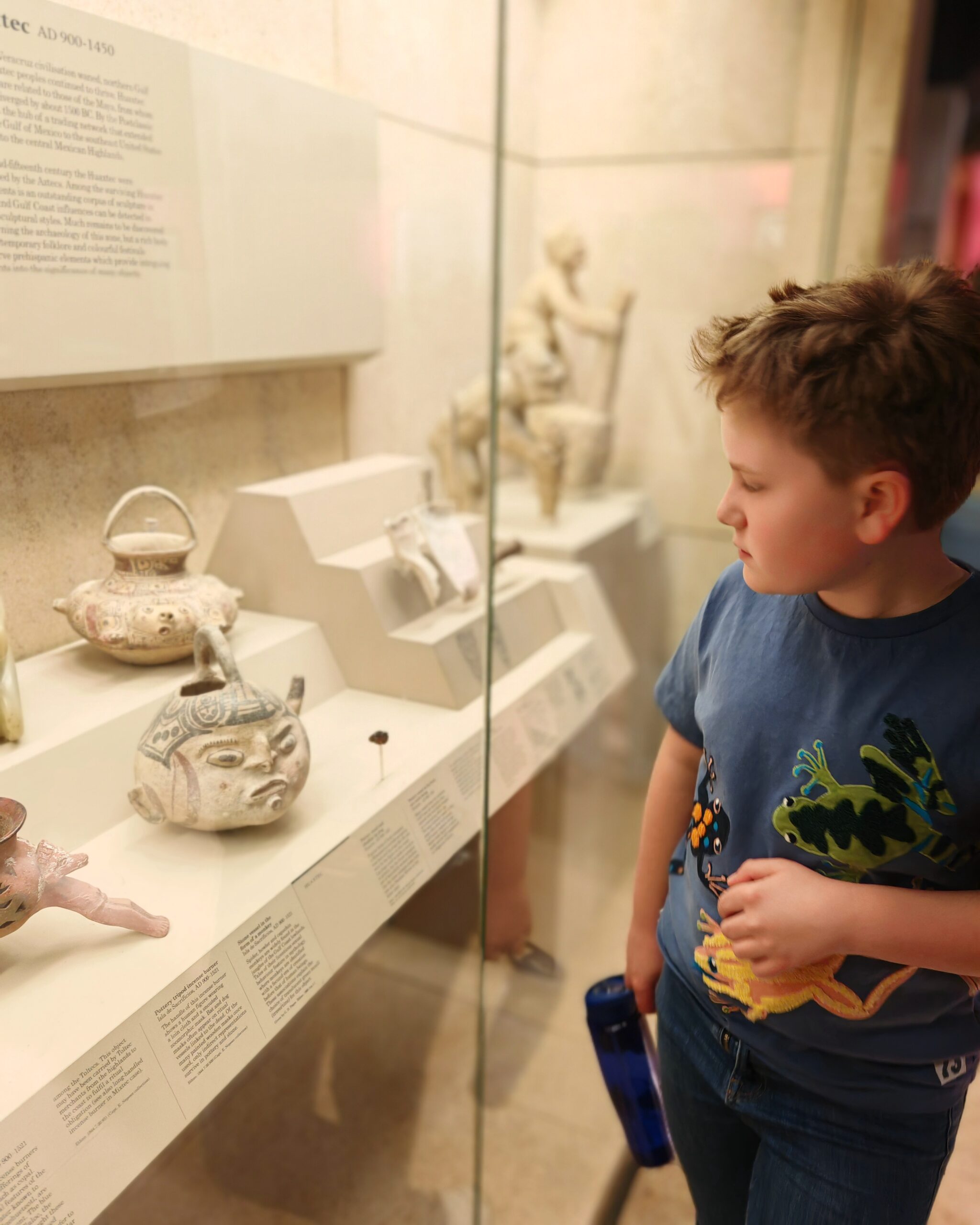 White boys with a blue tee-shirt looking at Asiatic artifacts on display at the British Museum in London White boys with a blue tee-shirt looking at Asiatic artifacts on display at the British Museum in London