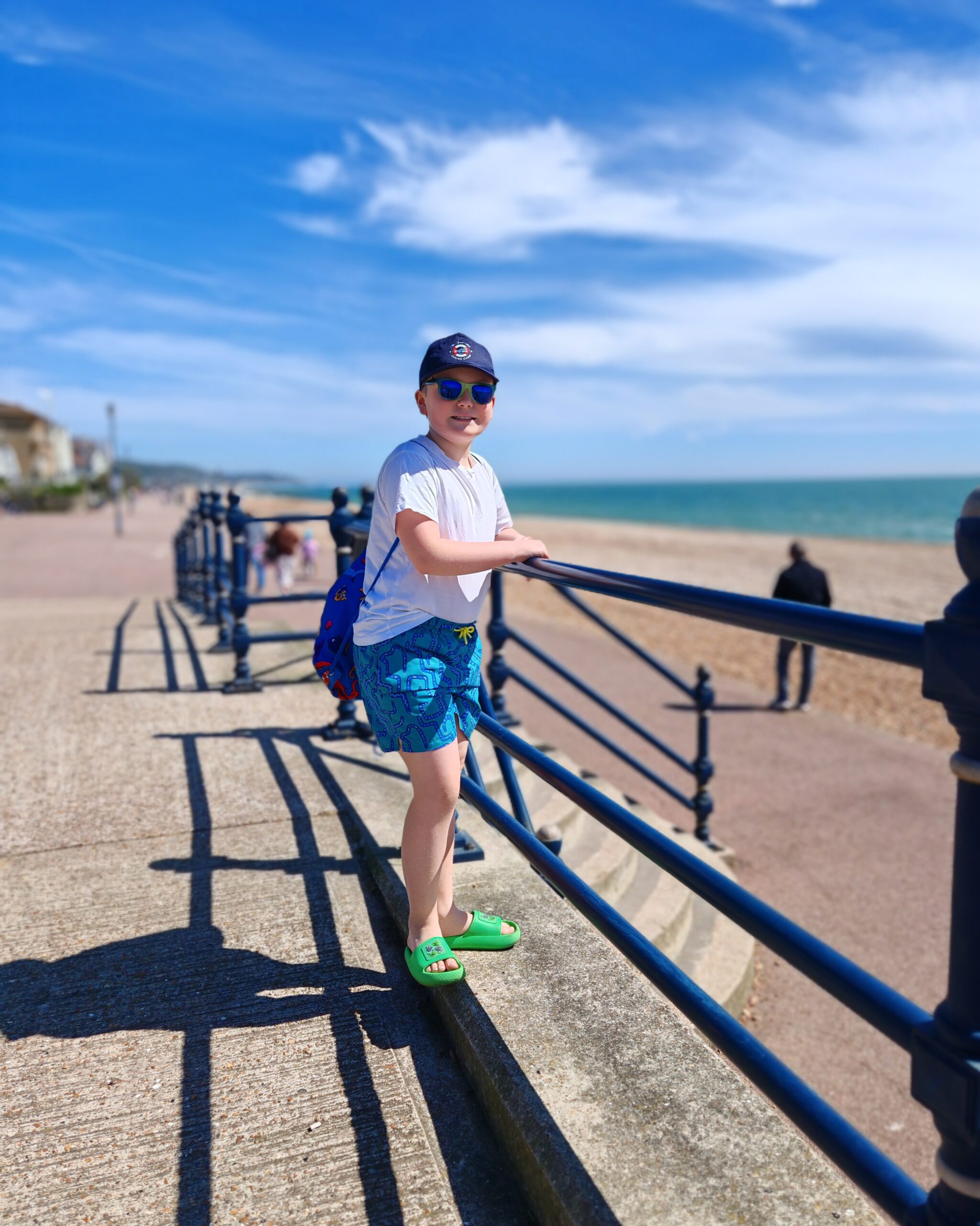 White boy with a white tee, shorts and cap on the seaside, walking along the beach in Hythe, Kenton a sunny day White boy with a white tee, shorts and cap on the seaside, walking along the beach in Hythe, Kenton a sunny day