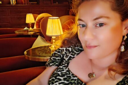 White woman wearing a leopard dress, sitting in a cinema room for a private viewing in Central London