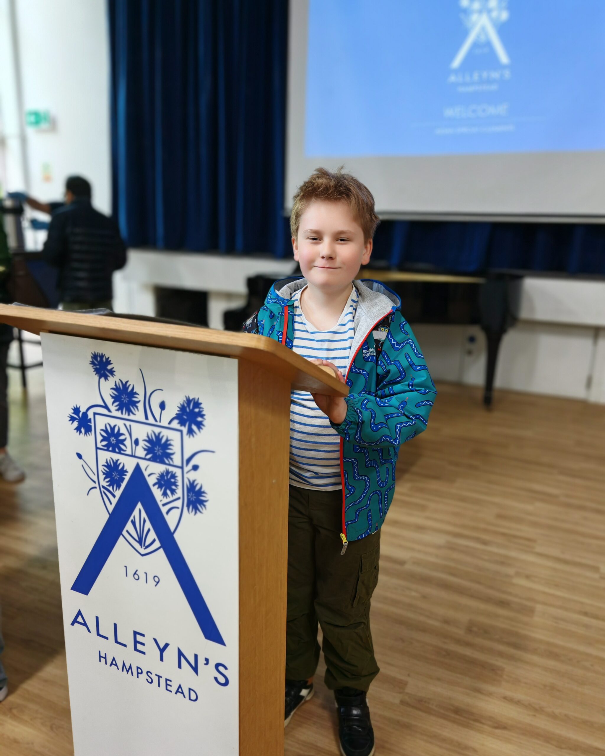 White little boy standing by an Alleyn's Hampstead stand during an open day for Alleyn's Hampstead in North London