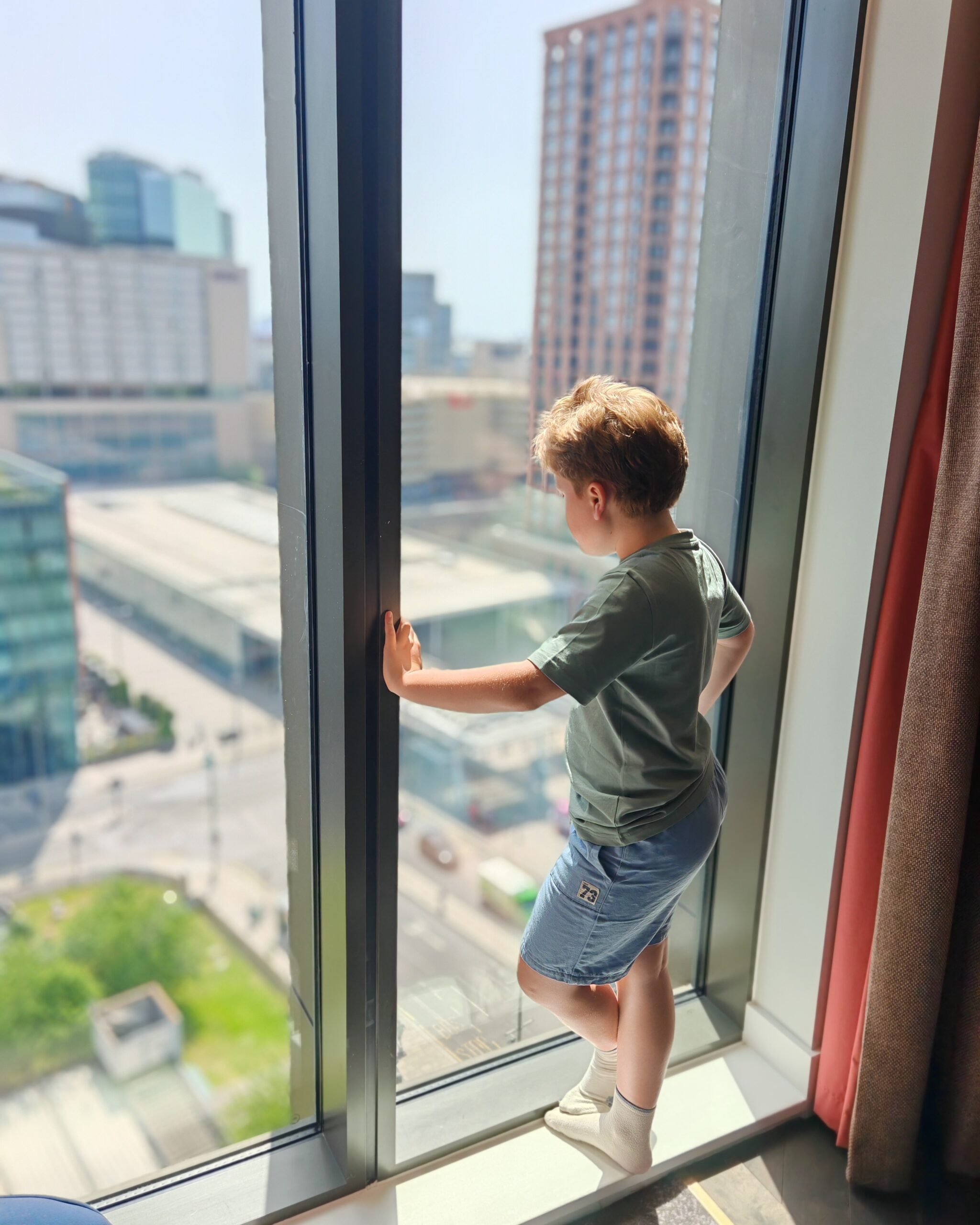 white little boy overlooking Stratford International while staying in a room at the Gantry Hotel, East London