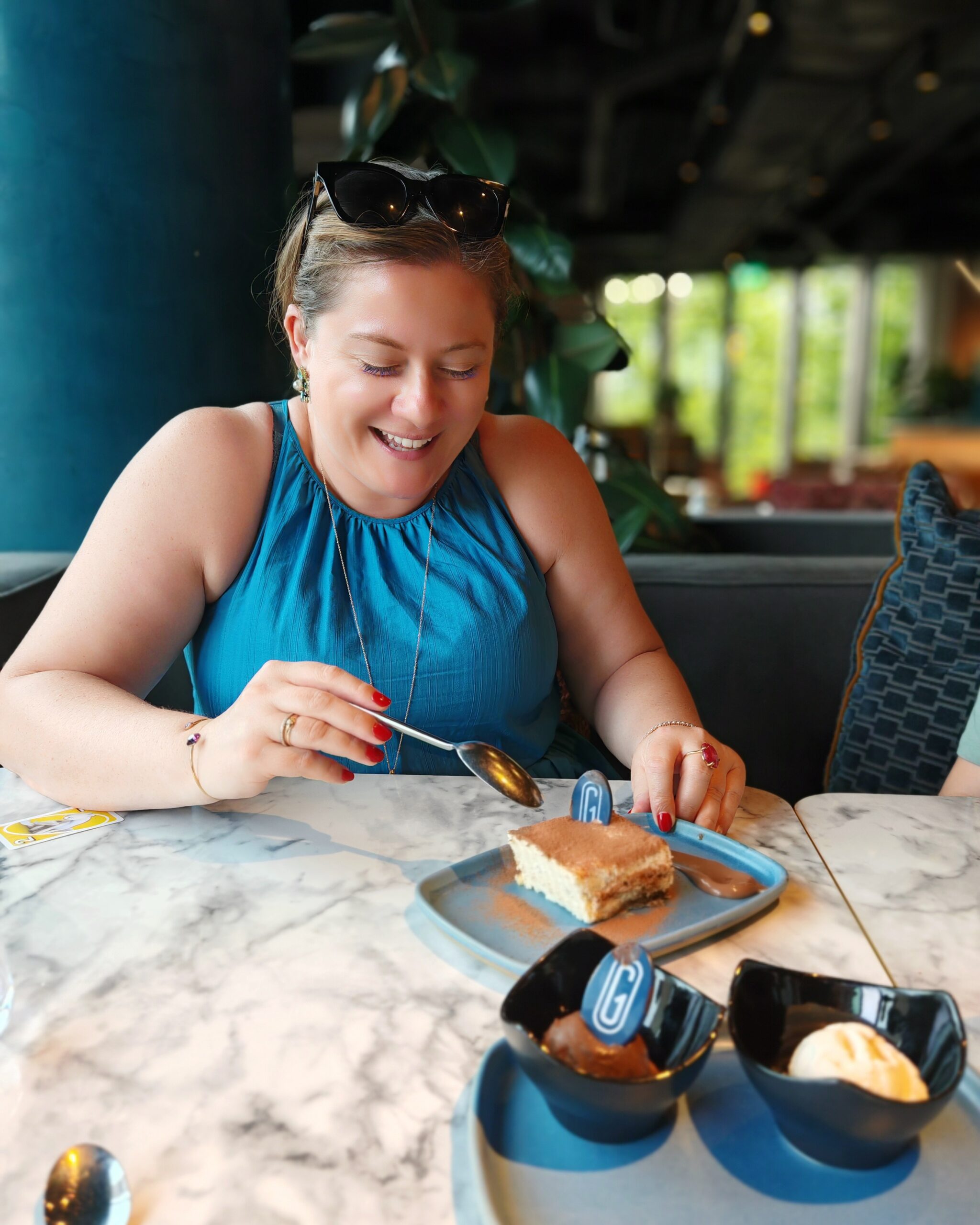 white woman wearing a blue top who is about to dive into a big piece of tiramisu cake at the Gantry Hotel