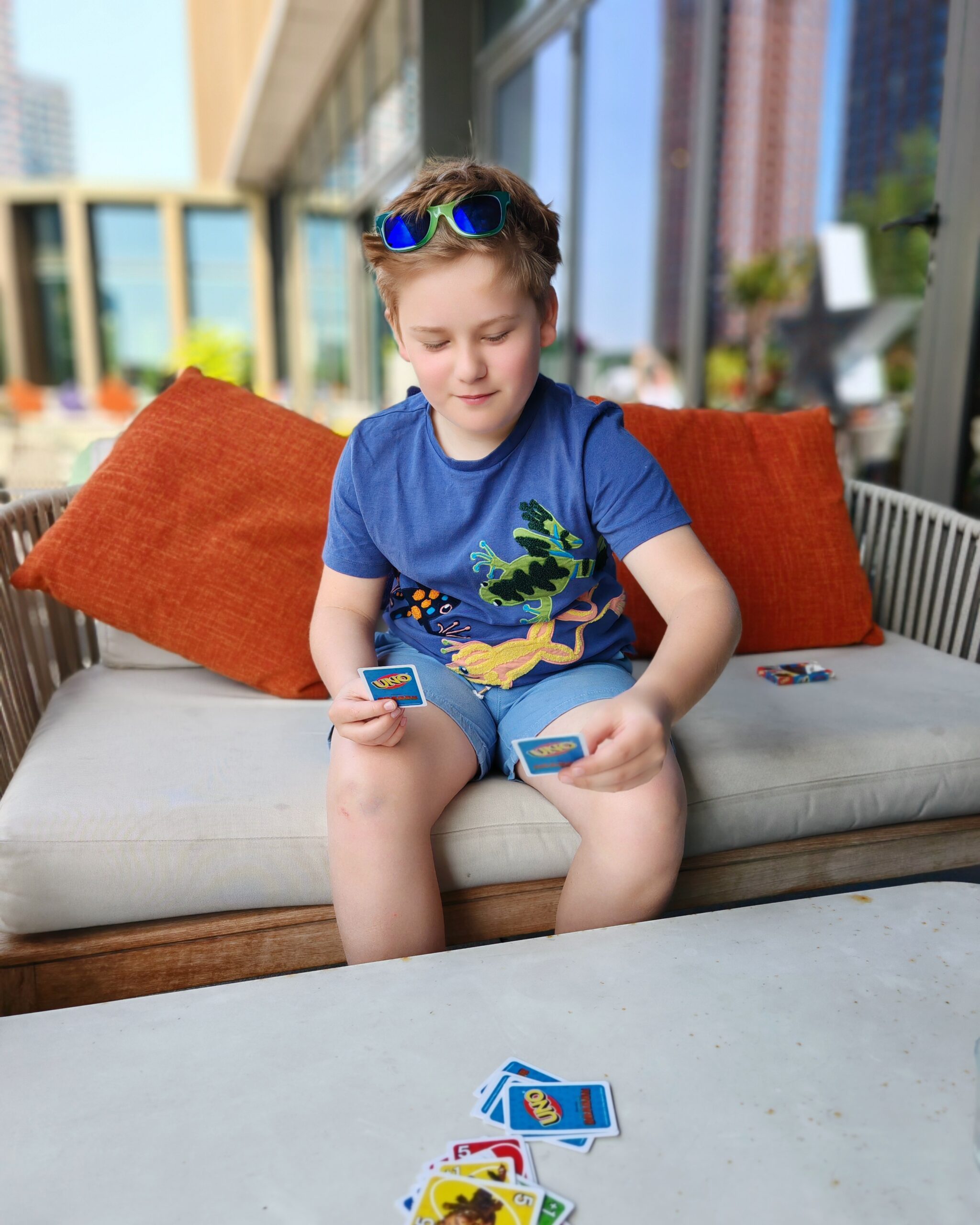 white little boy with a blue tee-shirt sitting on the terrace of Union Social at the Gantry Hotel in East London. He's playing UNO.