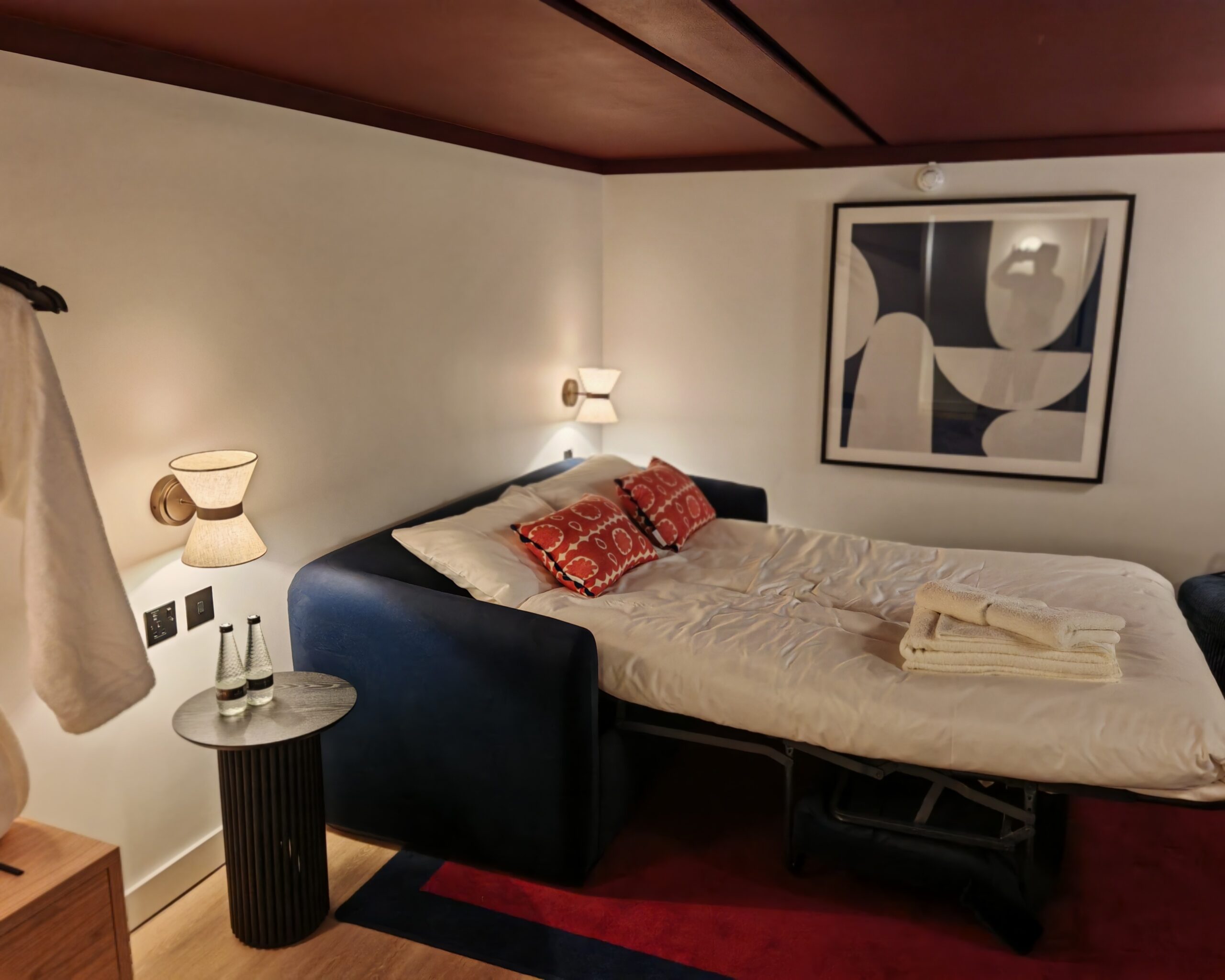 Living area in a studio at onefifty fenchurch, the sofa bed is now a bed for people to sleep with the nigh light one and bottles of water on the table Living area in a studio at onefifty fenchurch, the sofa bed is now a bed for people to sleep with the nigh light one and bottles of water on the table