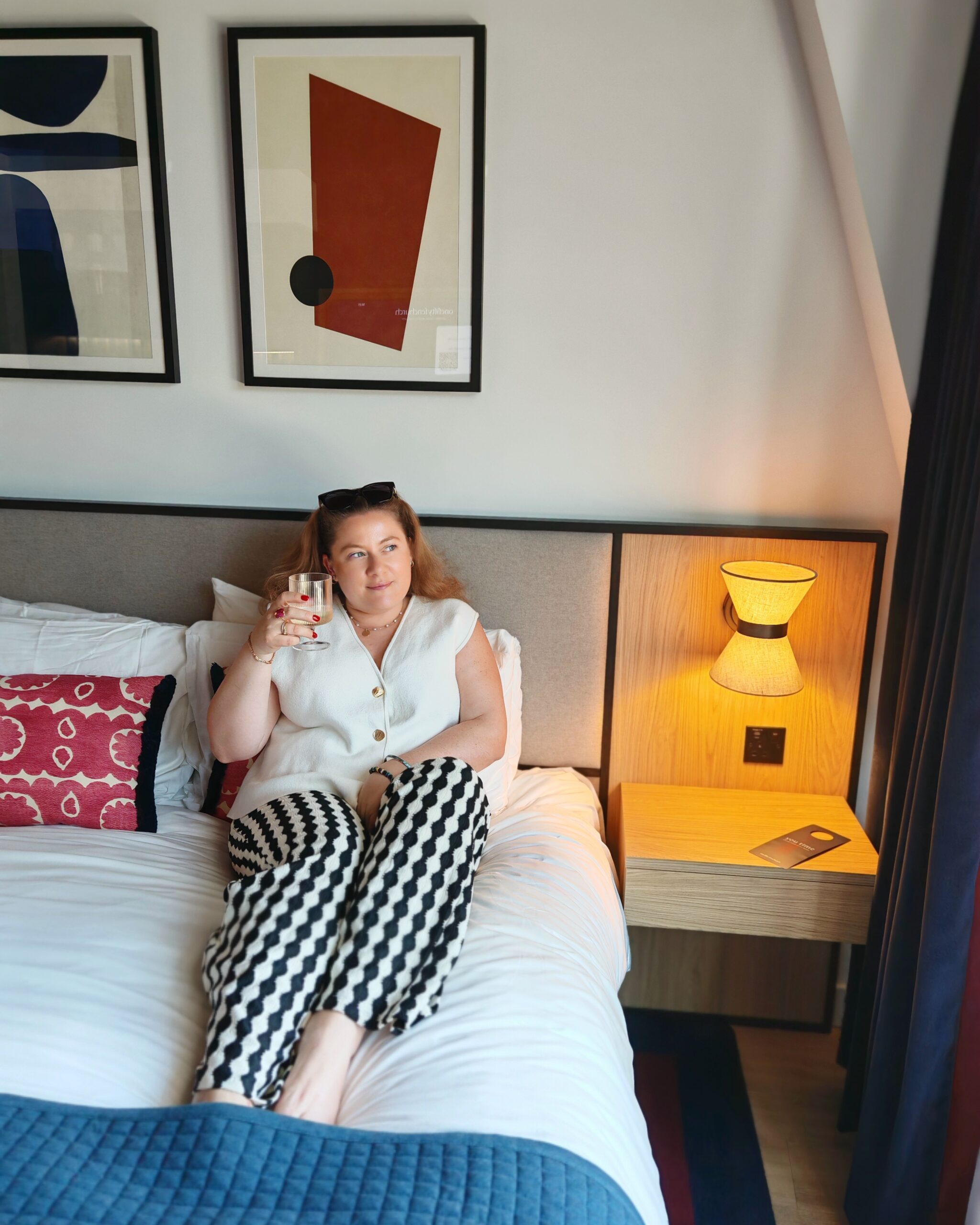 white woman with black and white trousers sitting on a king-size bed in a luxury boutique apart hotel in the City called Onefifty Fenchurch white woman with black and white trousers sitting on a king-size bed in a luxury boutique apart hotel in the City called Onefifty Fenchurch