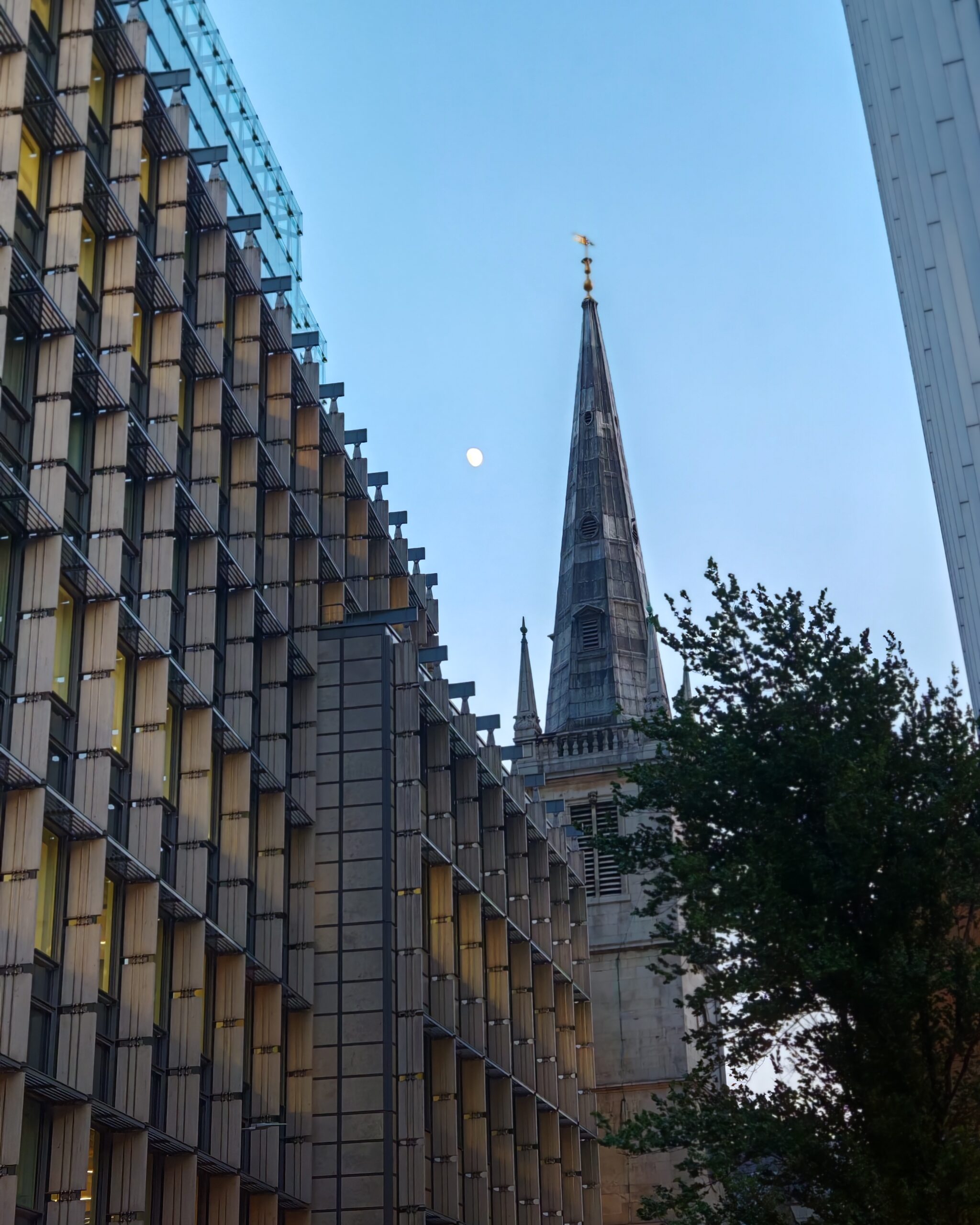 view from one studio at onefifty Fenchurch in the City District. You can see the moon right by a church among skyscrapers and modern building view from one studio at onefifty Fenchurch in the City District. You can see the moon right by a church among skyscrapers and modern building
