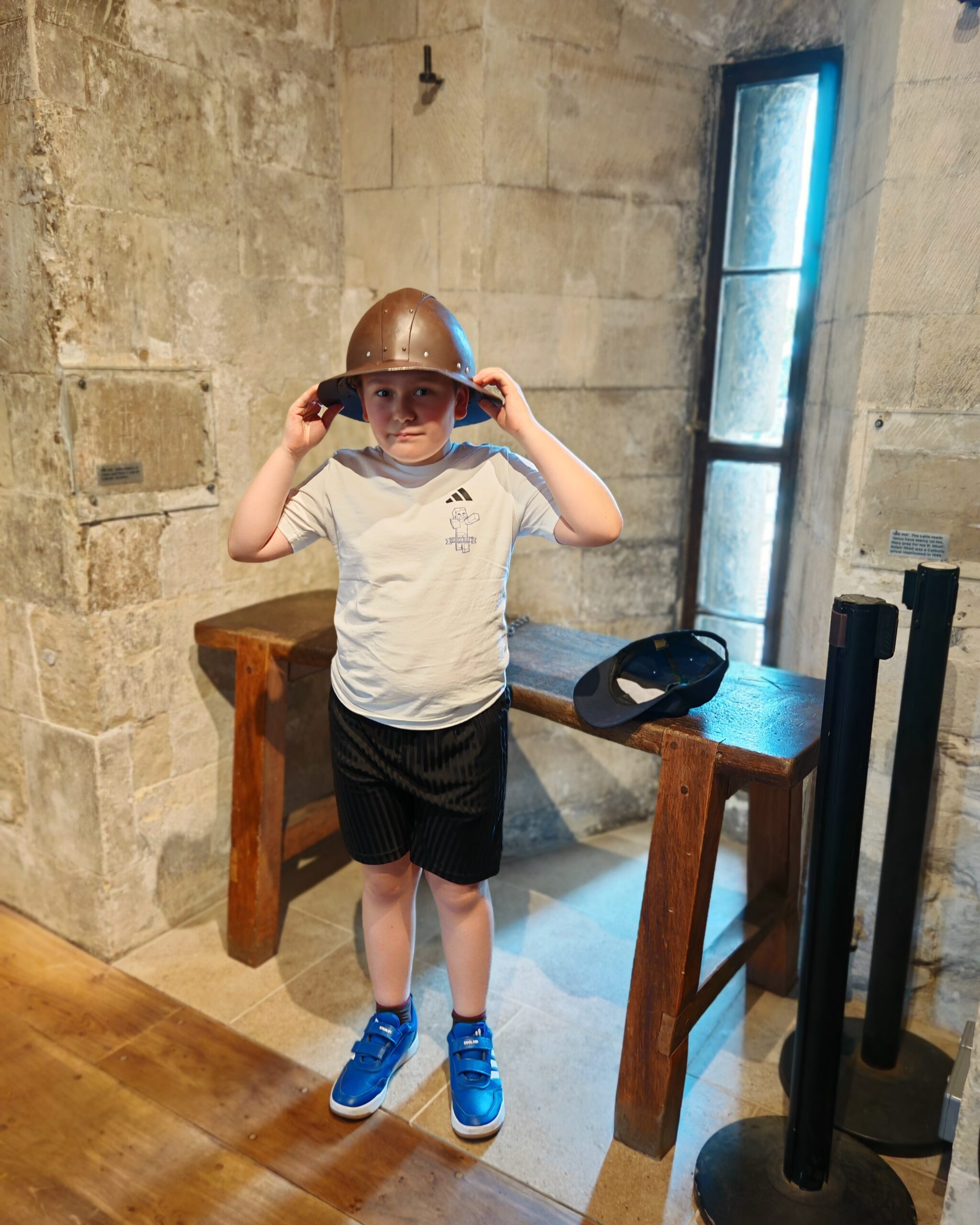 white little boy putting on a medieval helmet inside a gate at the Tower of London white little boy putting on a medieval helmet inside a gate at the Tower of London