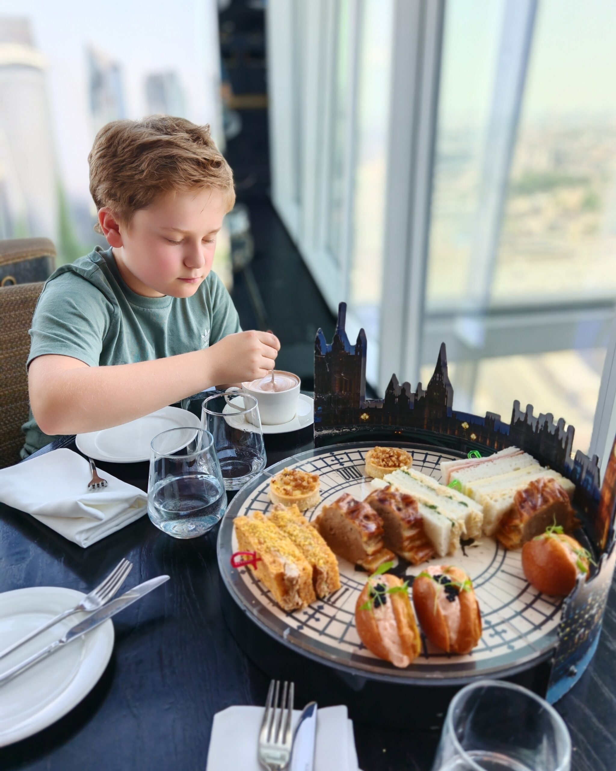 White Little Boy stirring a hot chocolate while eating the Peter Pan Afternoon Tea at the Aqua Shard restaurant in London White Little Boy stirring a hot chocolate while eating the Peter Pan Afternoon Tea at the Aqua Shard restaurant in London