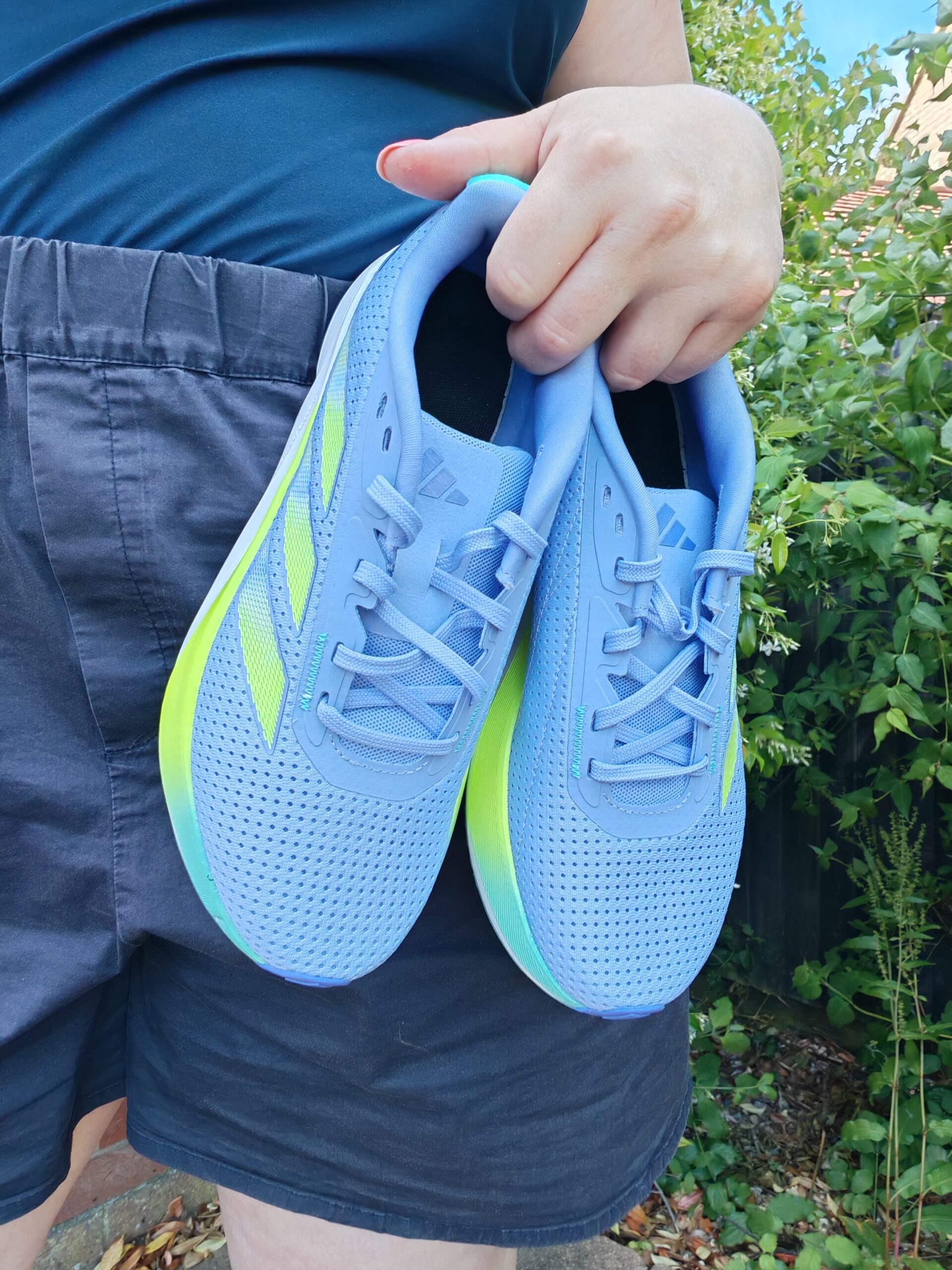 zoom on a white woman carrying a pair of adidas Women's Duramo SL2 Running Shoes in blue and yellow. zoom on a white woman carrying a pair of adidas Women's Duramo SL2 Running Shoes in blue and yellow.