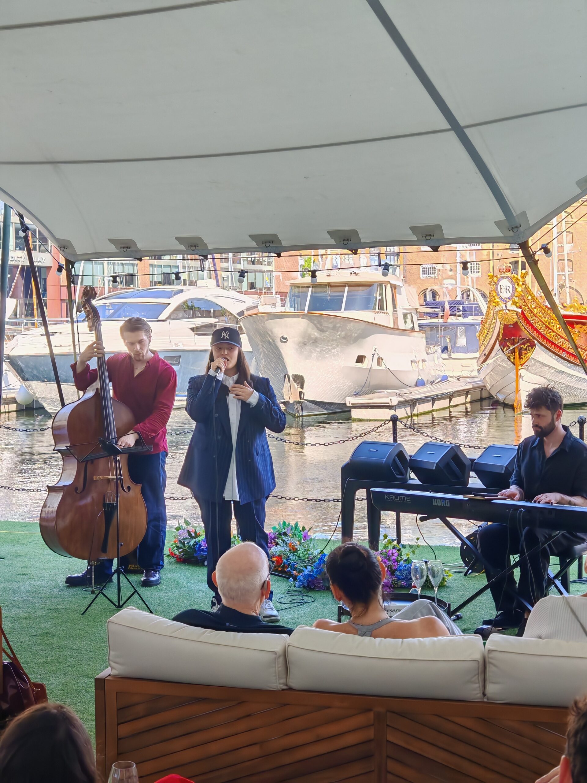 St Katharine Docks jazz session on the floating pontoon. A jazz singer is playing along a keyboard player and a double bass player St Katharine Docks jazz session on the floating pontoon. A jazz singer is playing along a keyboard player and a double bass player