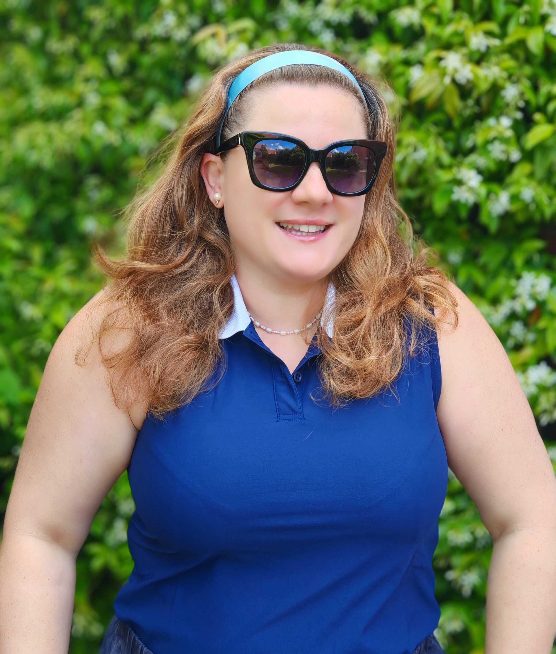 White woman with chesnut hair smiling at the camera with an adidas blue top form the Wimbledon collection White woman with chesnut hair smiling at the camera with an adidas blue top form the Wimbledon collection