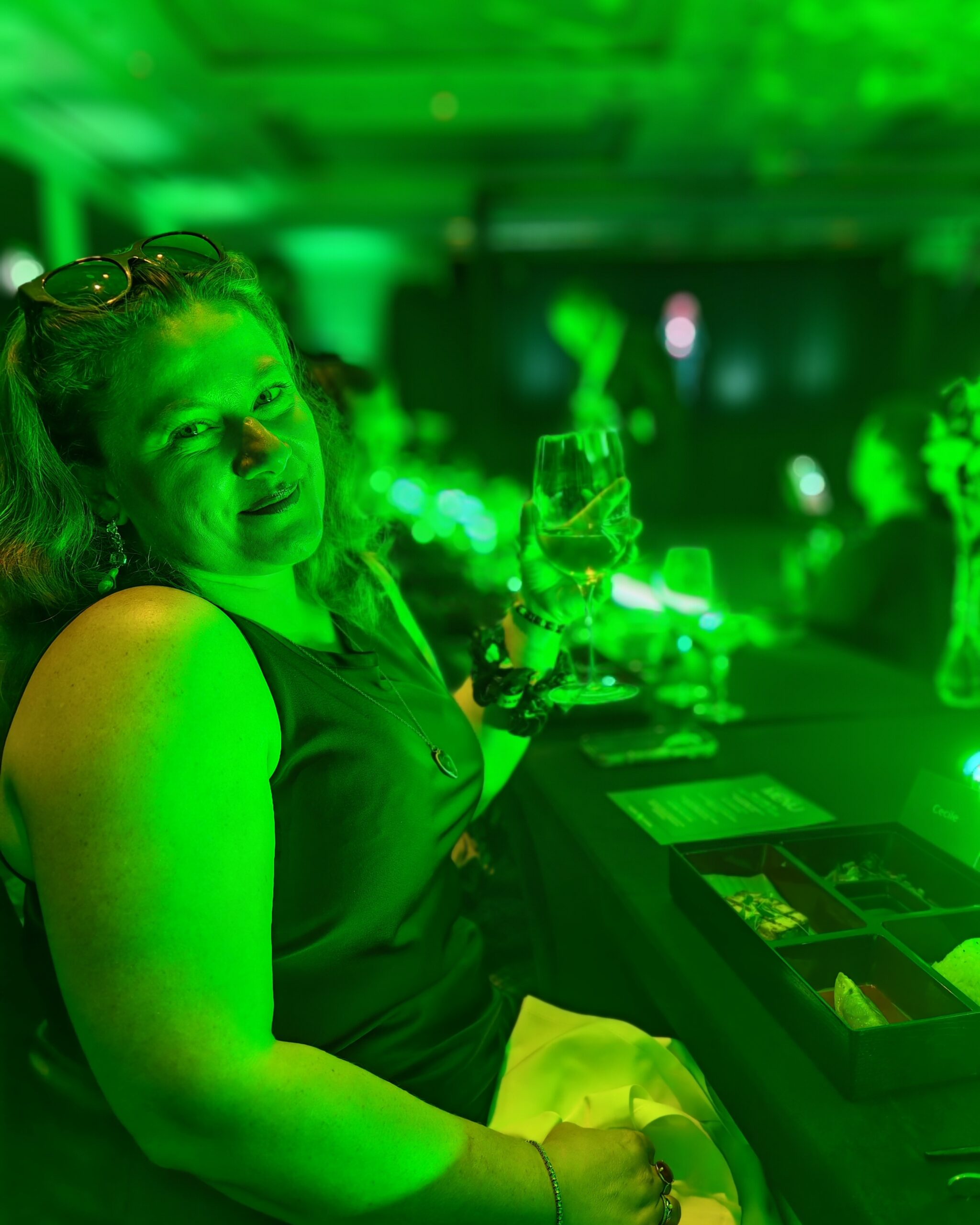 White woman in a black dress holding a wine glass while enjoying a futuristic diner at Pullman St Pancras Hotel White woman in a black dress holding a wine glass while enjoying a futuristic diner at Pullman St Pancras Hotel