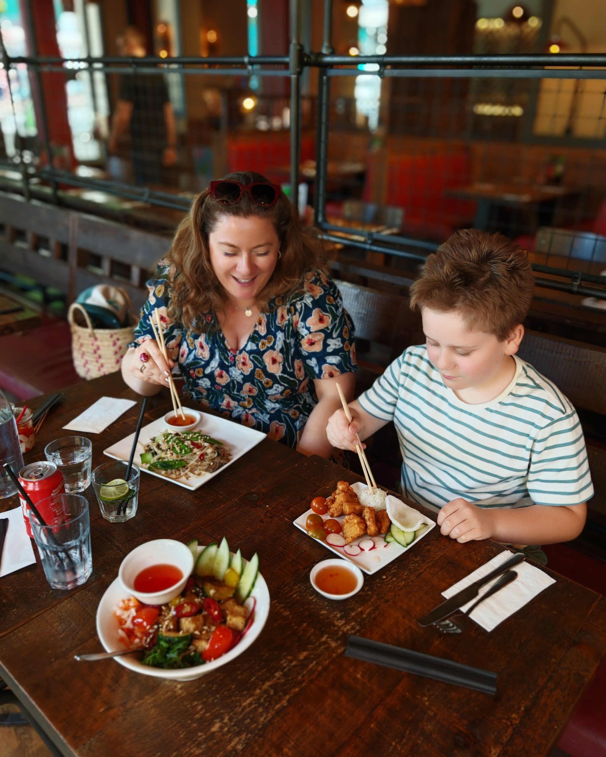 White woman and little boy eating Vietnamese food at Pho in Tunbridge Wells with pad Thai and chicken on the table White woman and little boy eating Vietnamese food at Pho in Tunbridge Wells with pad Thai and chicken on the table