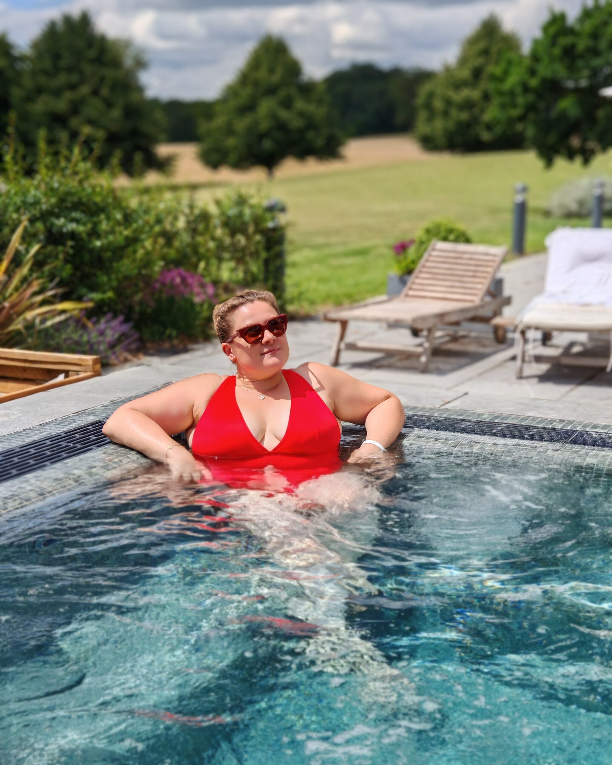 White woman in a bright red swimming costume relaxing in the outdoor pool at Eastwell Manor Champneys Spa near Ashford in Kent