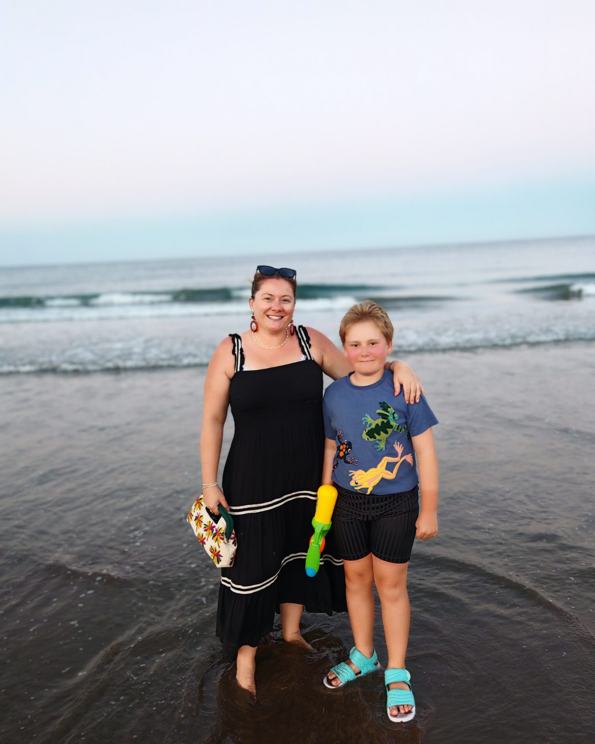 White woman in a black dress with her son, posing on the beach of Maspalomas in Gran Canaria White woman in a black dress with her son, posing on the beach of Maspalomas in Gran Canaria
