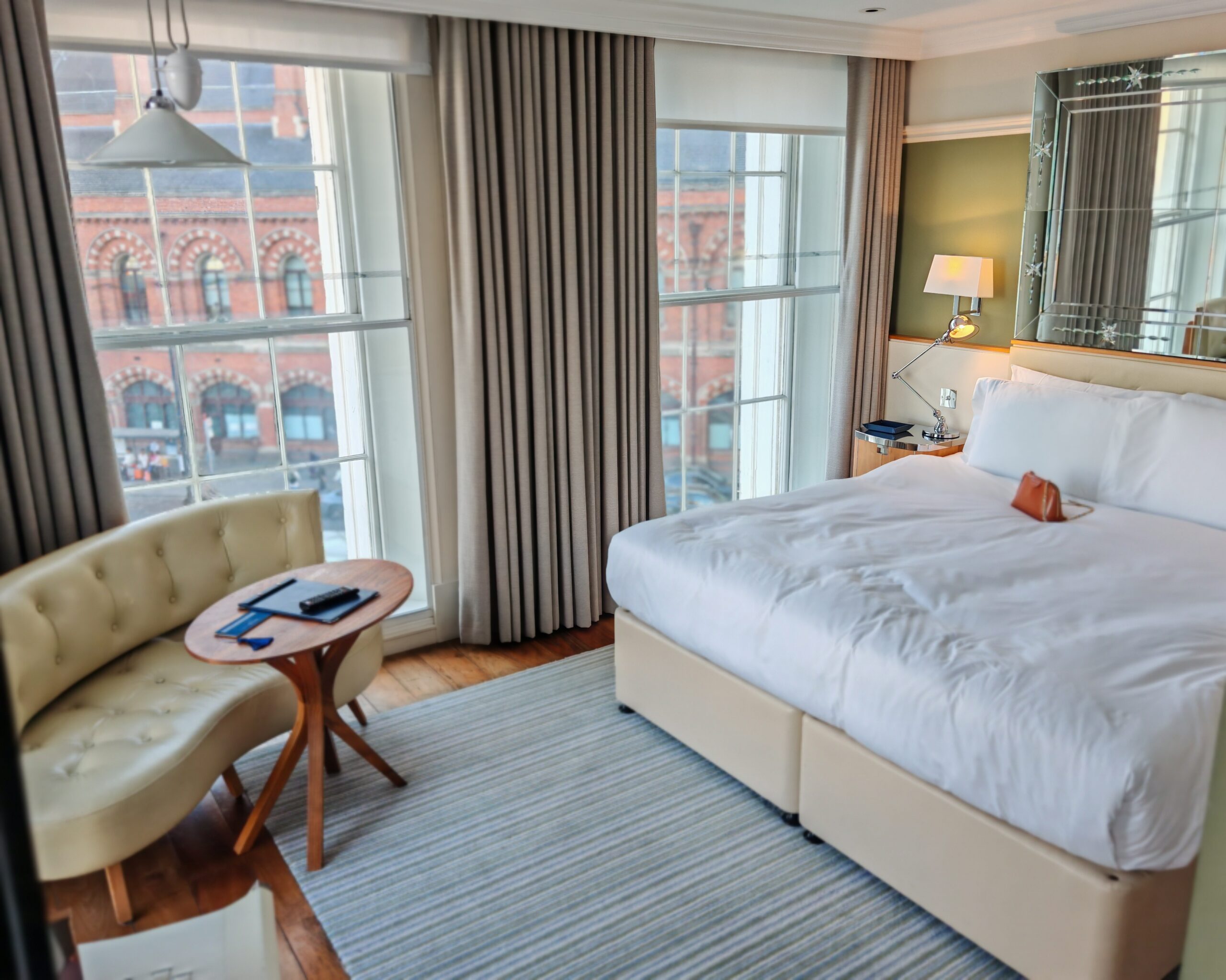 Room at the Kaya Great Northern Hotel in Central London, made of a king-sized bed and a chair with table space. You can see St Pancras International in the background