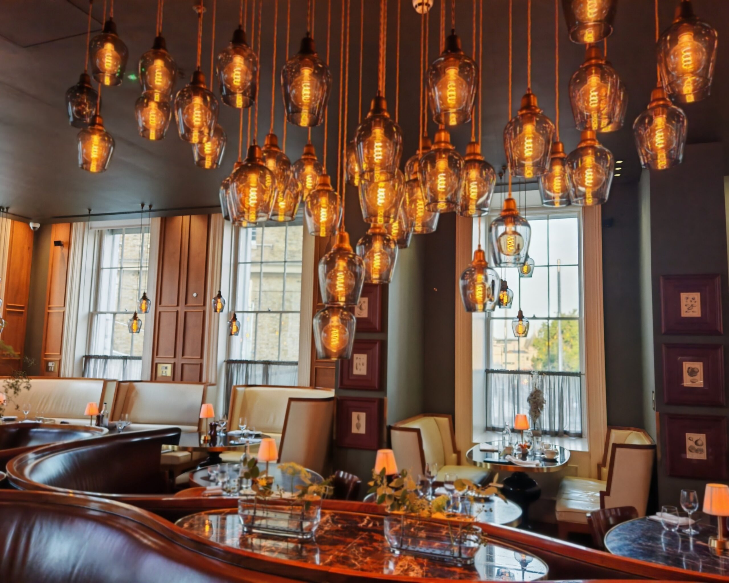 Interiors of the Rails Restaurant in Central London with high ceiling lights right above a set of table in a Parisian setting