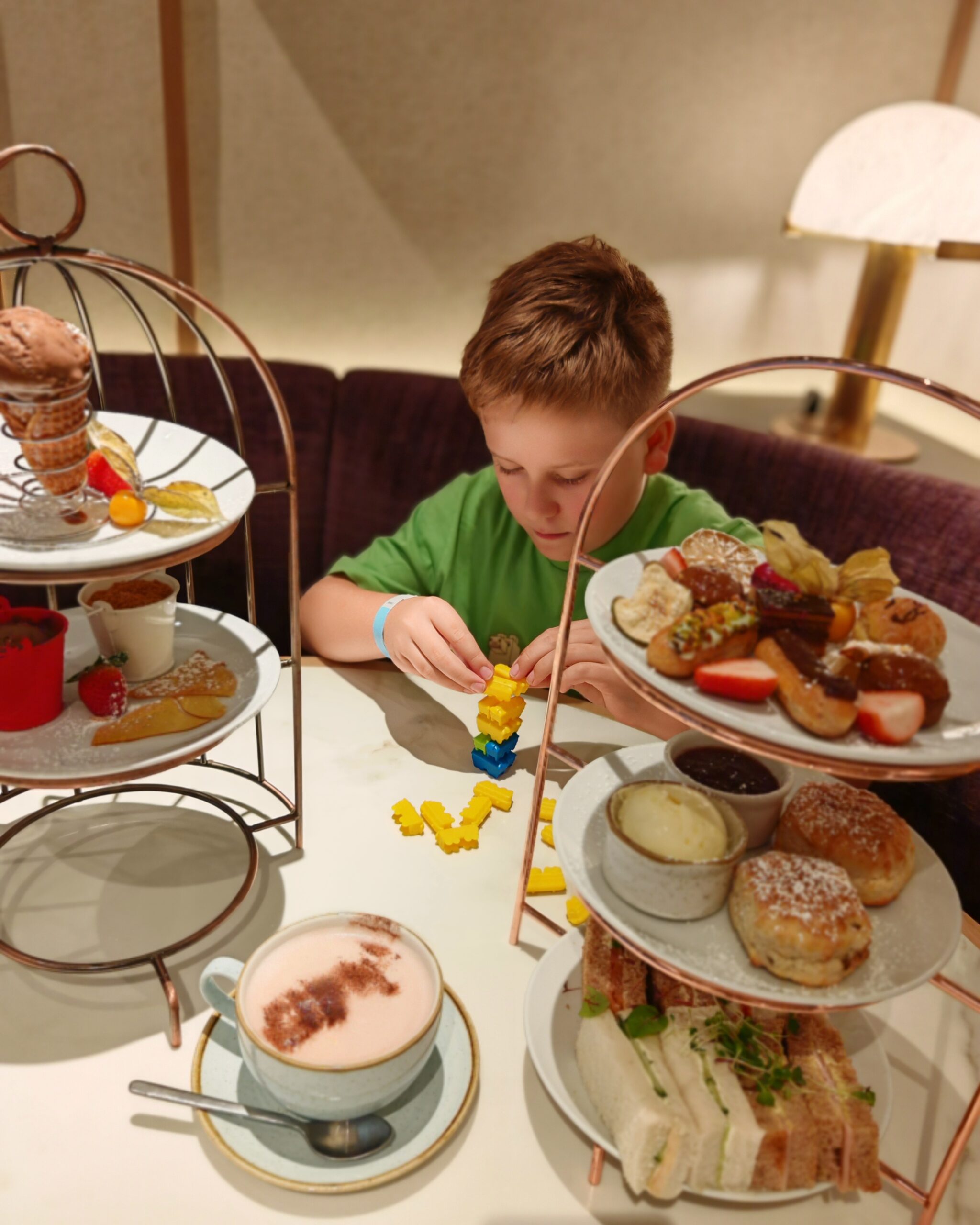 White little boy in a green tee-shirt enjoying an afternoon tea at the DoubleTree Hilton Victoria hotel