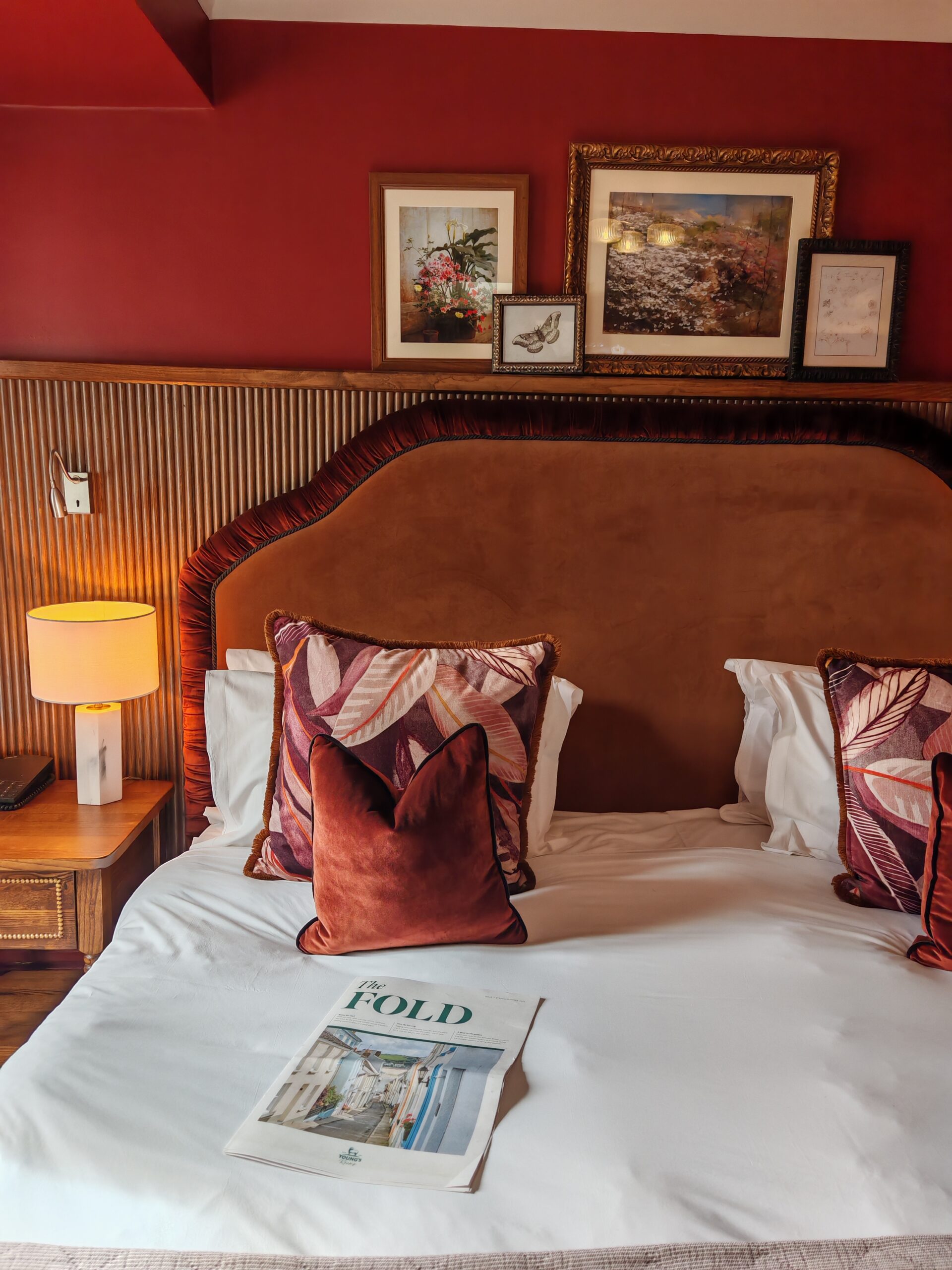 King size bed with a red bed head and multiple red velvet cushions on it and a copy of the fold newspaper laid down. King size bed with a red bed head and multiple red velvet cushions on it and a copy of the fold newspaper laid down.