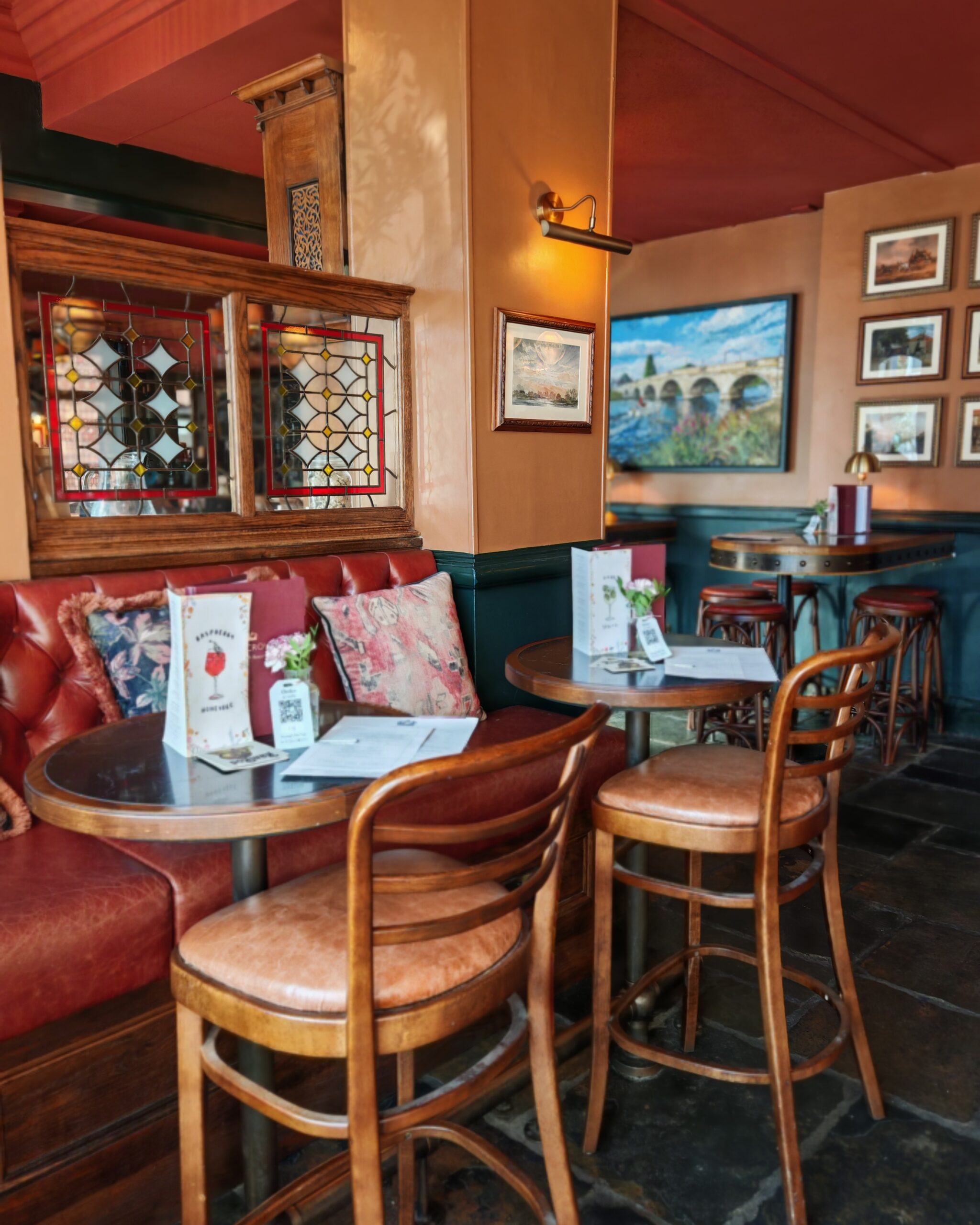 Living area of the Crown Pub in Chertsey, with wooden chairs and table and lots of frames and paintings in the background Living area of the Crown Pub in Chertsey, with wooden chairs and table and lots of frames and paintings in the background