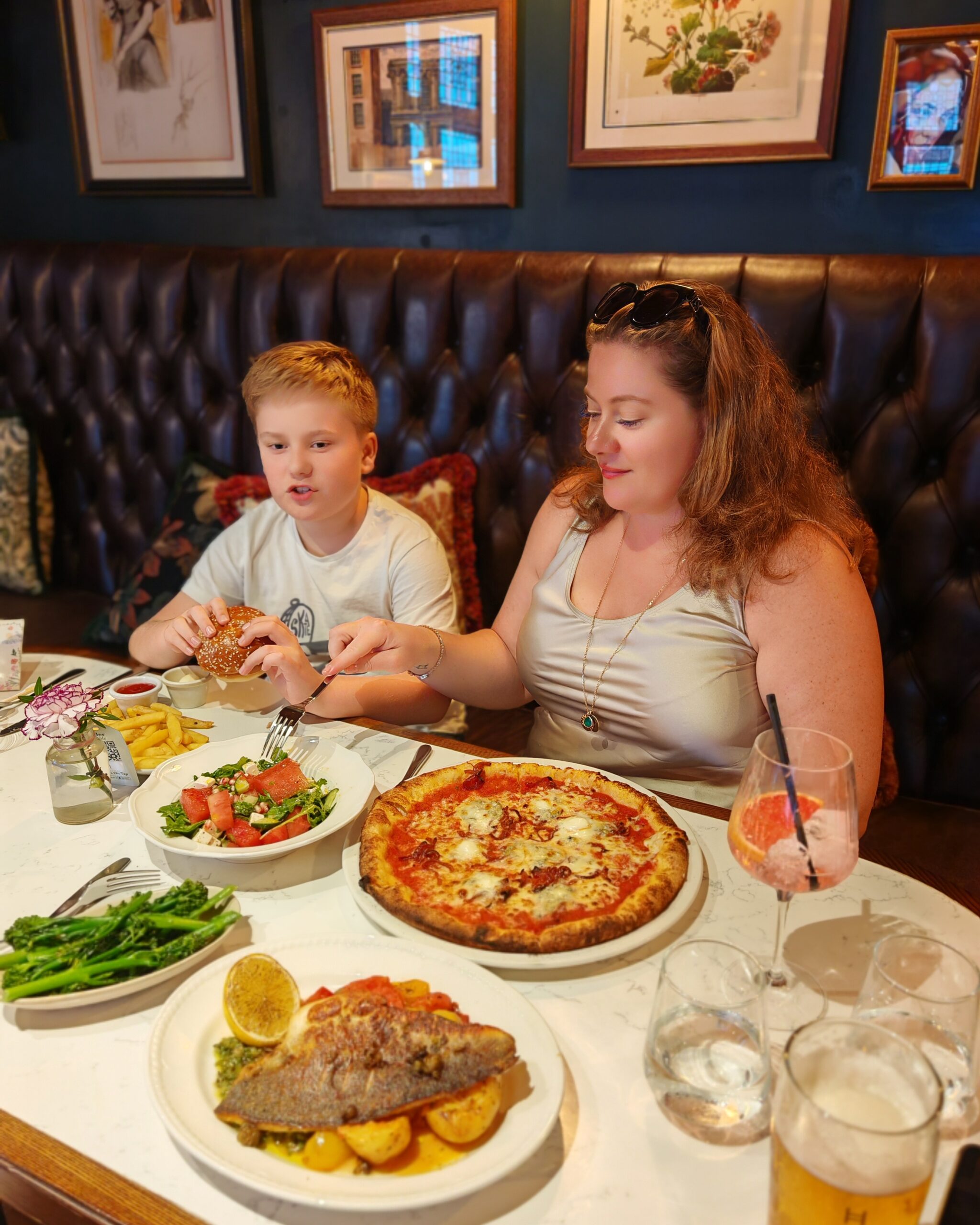 White woman in a satin dress with a little white boy eating dinner at the pub. He's having fish and she's eating pizza and a side of salad White woman in a satin dress with a little white boy eating dinner at the pub. He's having fish and she's eating pizza and a side of salad