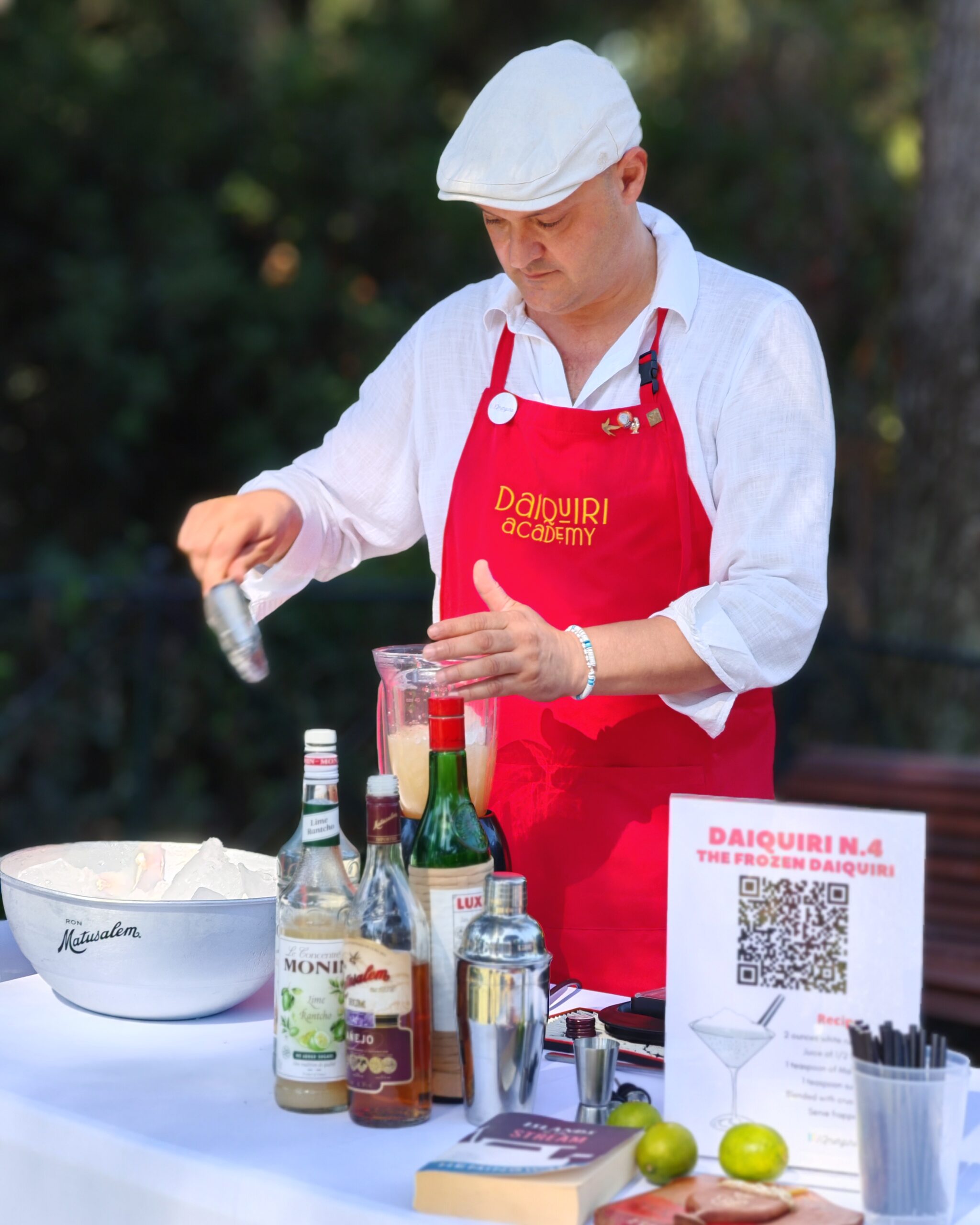 white man with a white cap and a red apron 'daiquiri workshop' preparing a cocktail with ice and lemons white man with a white cap and a red apron 'daiquiri workshop' preparing a cocktail with ice and lemons