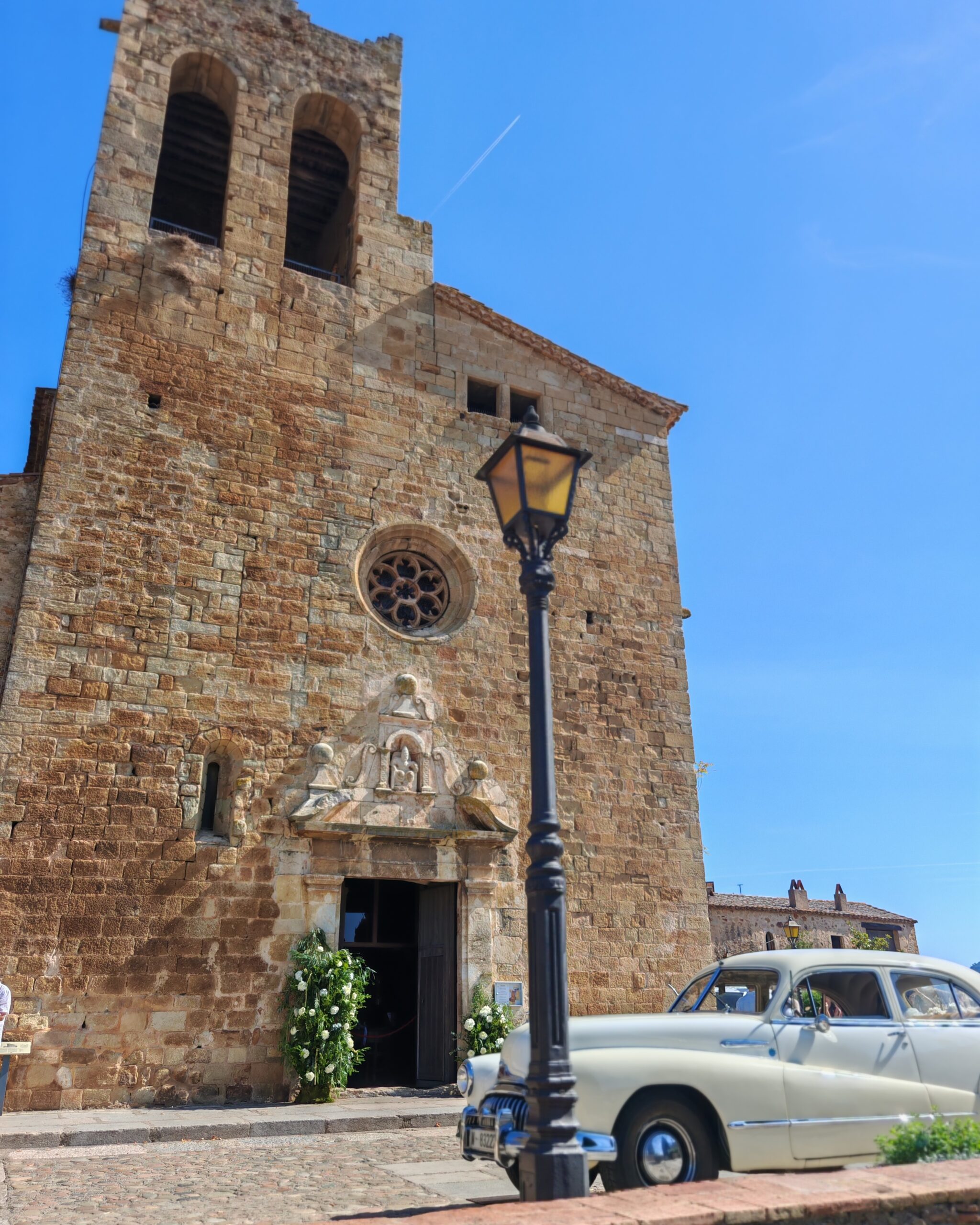 church of Pals, in Catalonia Spain with a vintage white car in front of the entrance, parked for a wedding ceremony taking place there church of Pals, in Catalonia Spain with a vintage white car in front of the entrance, parked for a wedding ceremony taking place there