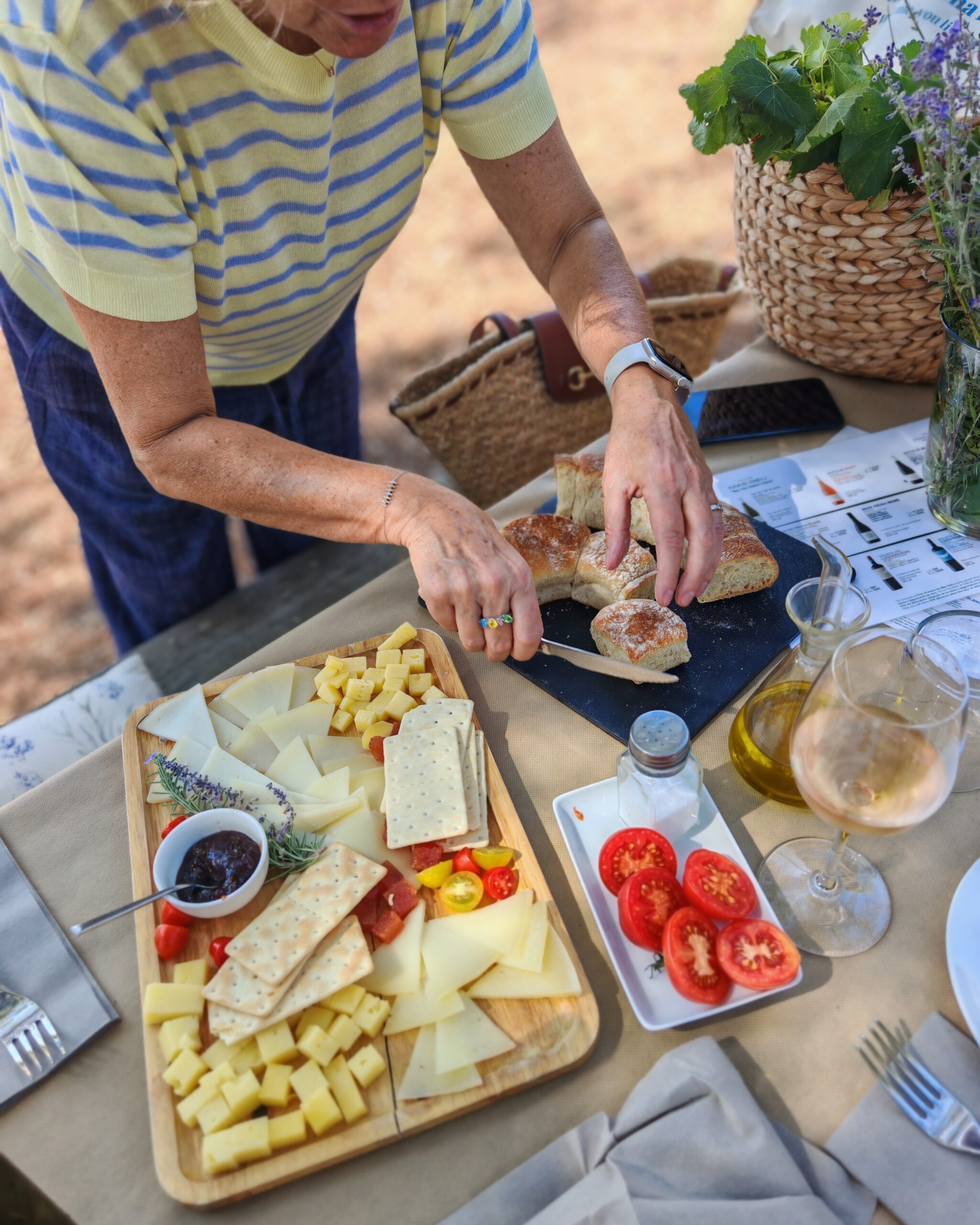 white woman in a stripped blue and yellow jumper preparing pan con tomate during a picnic, with cheese and ham next to her white woman in a stripped blue and yellow jumper preparing pan con tomate during a picnic, with cheese and ham next to her