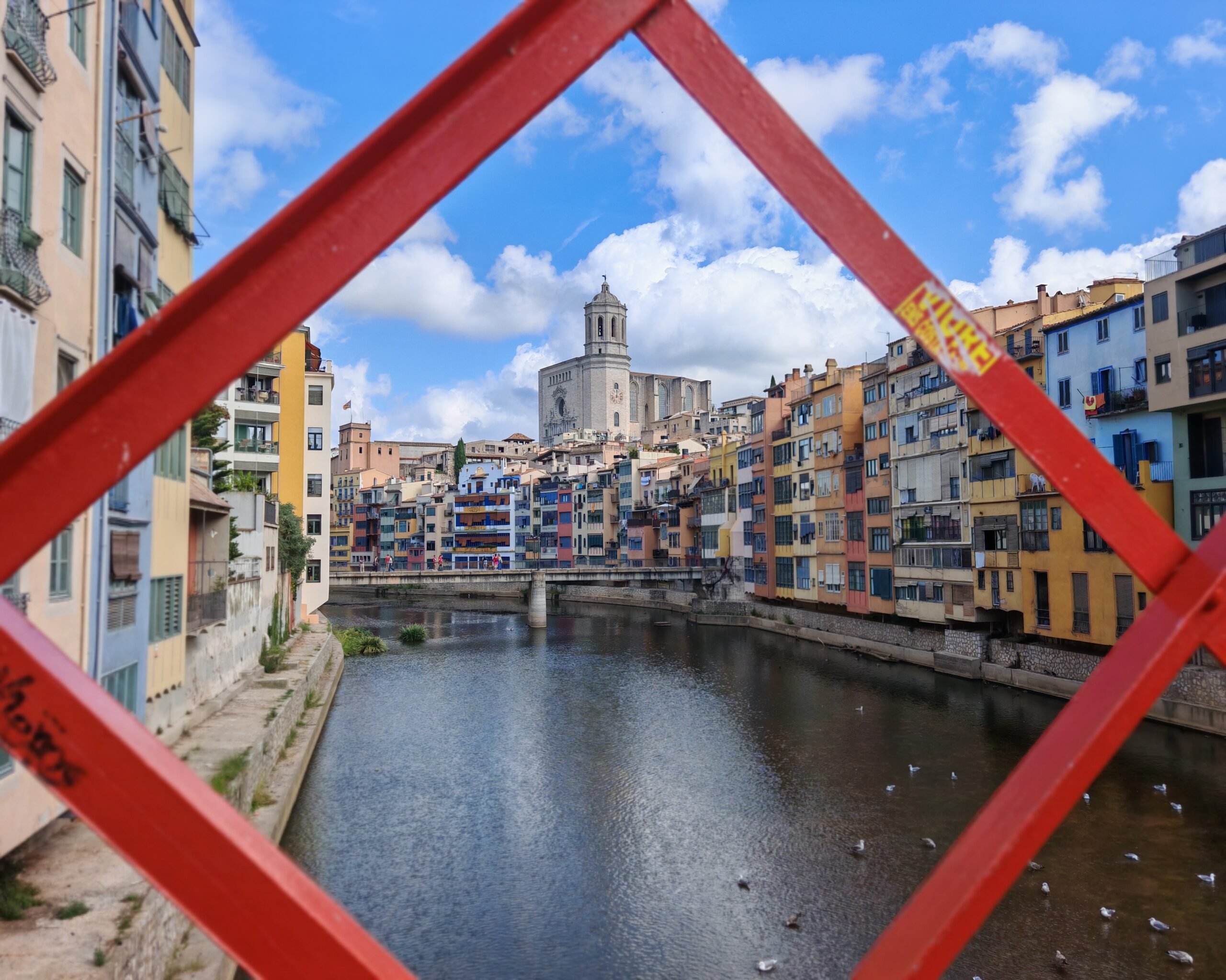 The Eiffel Bridge in Girona, officially known as the Pont de les Peixateries Velles (or Pont de Ferro), is a bright red, pedestrian-only iron bridge spanning the Onyar River The Eiffel Bridge in Girona, officially known as the Pont de les Peixateries Velles (or Pont de Ferro), is a bright red, pedestrian-only iron bridge spanning the Onyar River